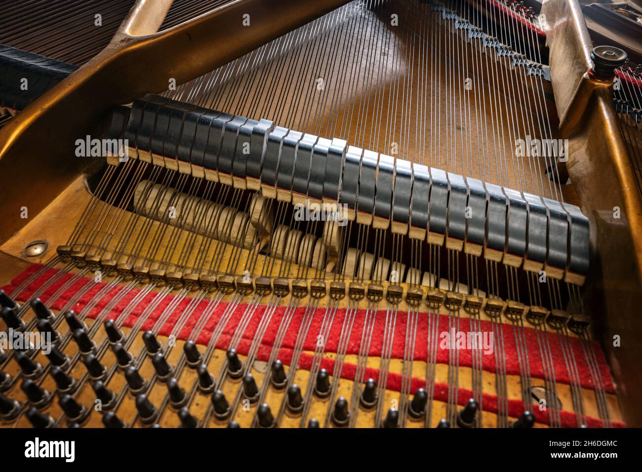 View to hammer and damper on the strings inside an older grand piano, part of the mechanics in the acoustic musical instrument, selected focus, narrow Stock Photo