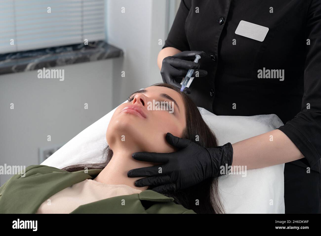Young woman with hair problem receiving injection in head skin in a clinic. Mesotherapy treatment of hair loss, injection for hair growth Stock Photo