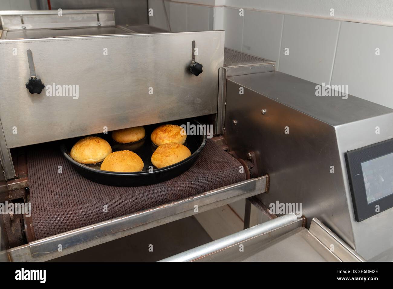 Baking production line. Freshly baked burger buns coming out of the