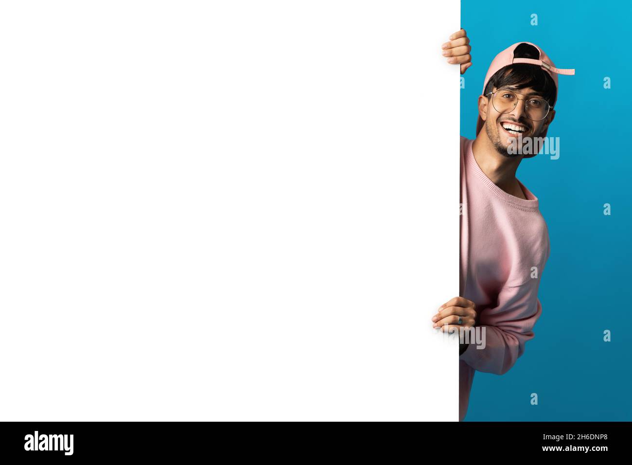 Positive millennial middle eastern man standing by blank board Stock Photo