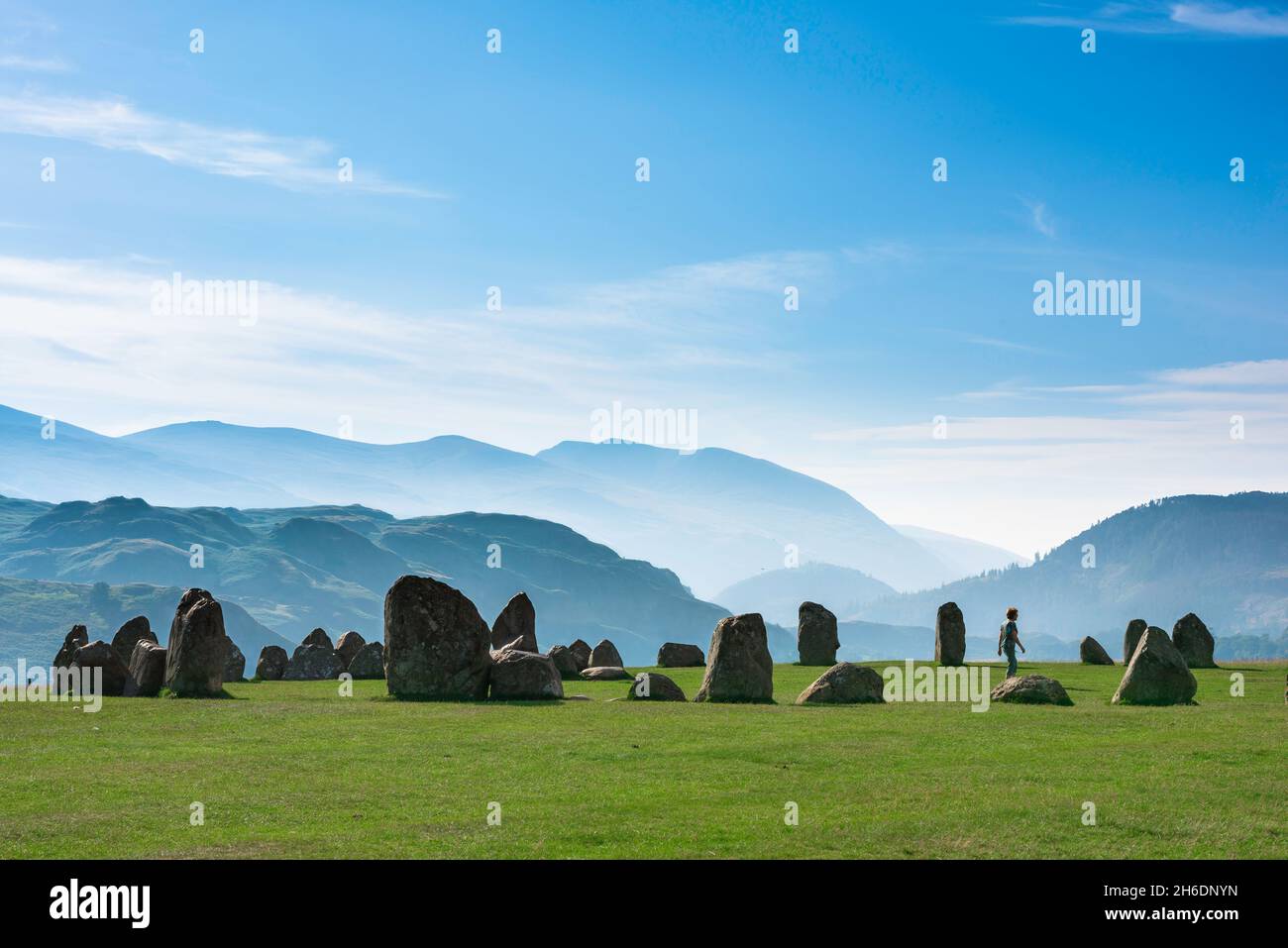 Stone circle UK, view on a summer morning of a woman walking inside an ancient stone circle against a backdrop of mountains, Castlerigg, Cumbria, UK Stock Photo
