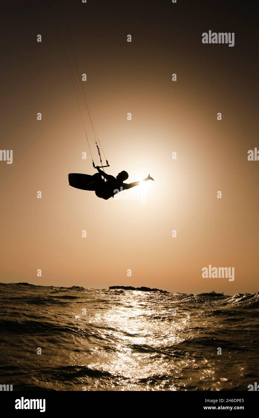 Silhouette of a kitesurfer Kitesurfing at sun set in the Mediterranean sea Photographed from within the water Stock Photo