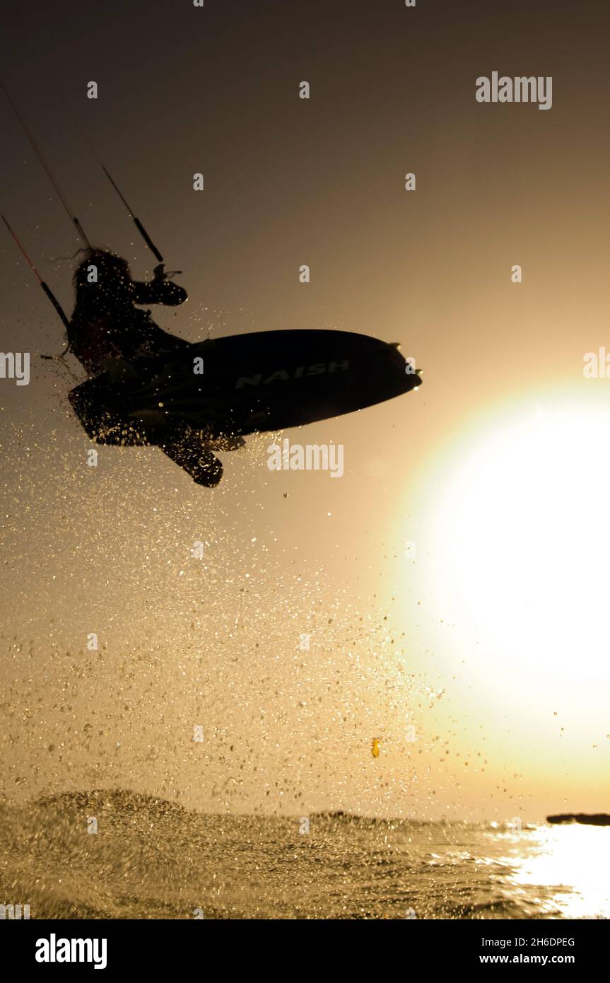 Silhouette of a kitesurfer Kitesurfing at sun set in the Mediterranean sea Photographed from within the water Stock Photo