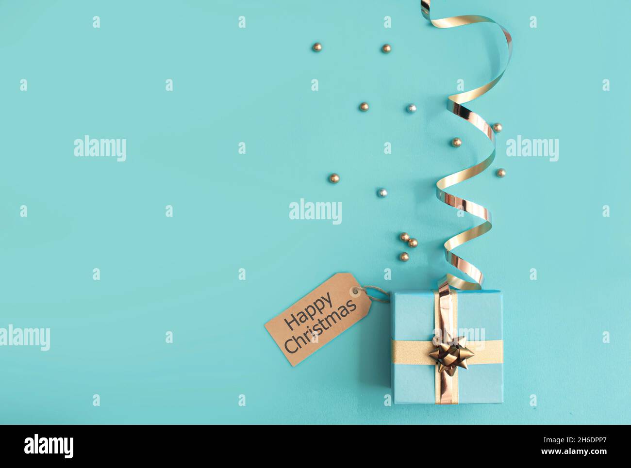 Seasonal gift box wrapped with with gold ribbon bow and greeting card