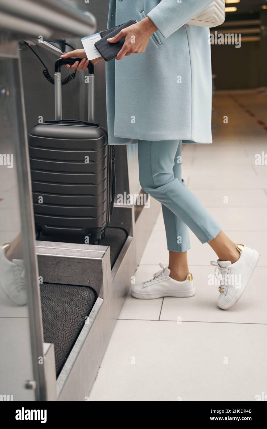 Passenger using selfservice baggage dropoff unit at airport Stock