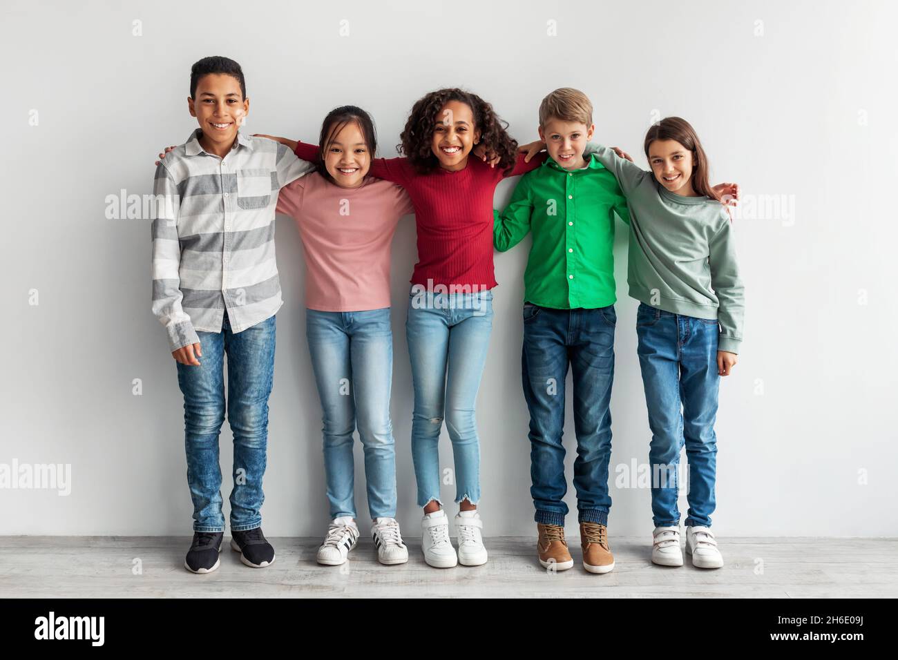 Group Of Happy Diverse Preteen Children Embracing Over Gray Background Stock Photo
