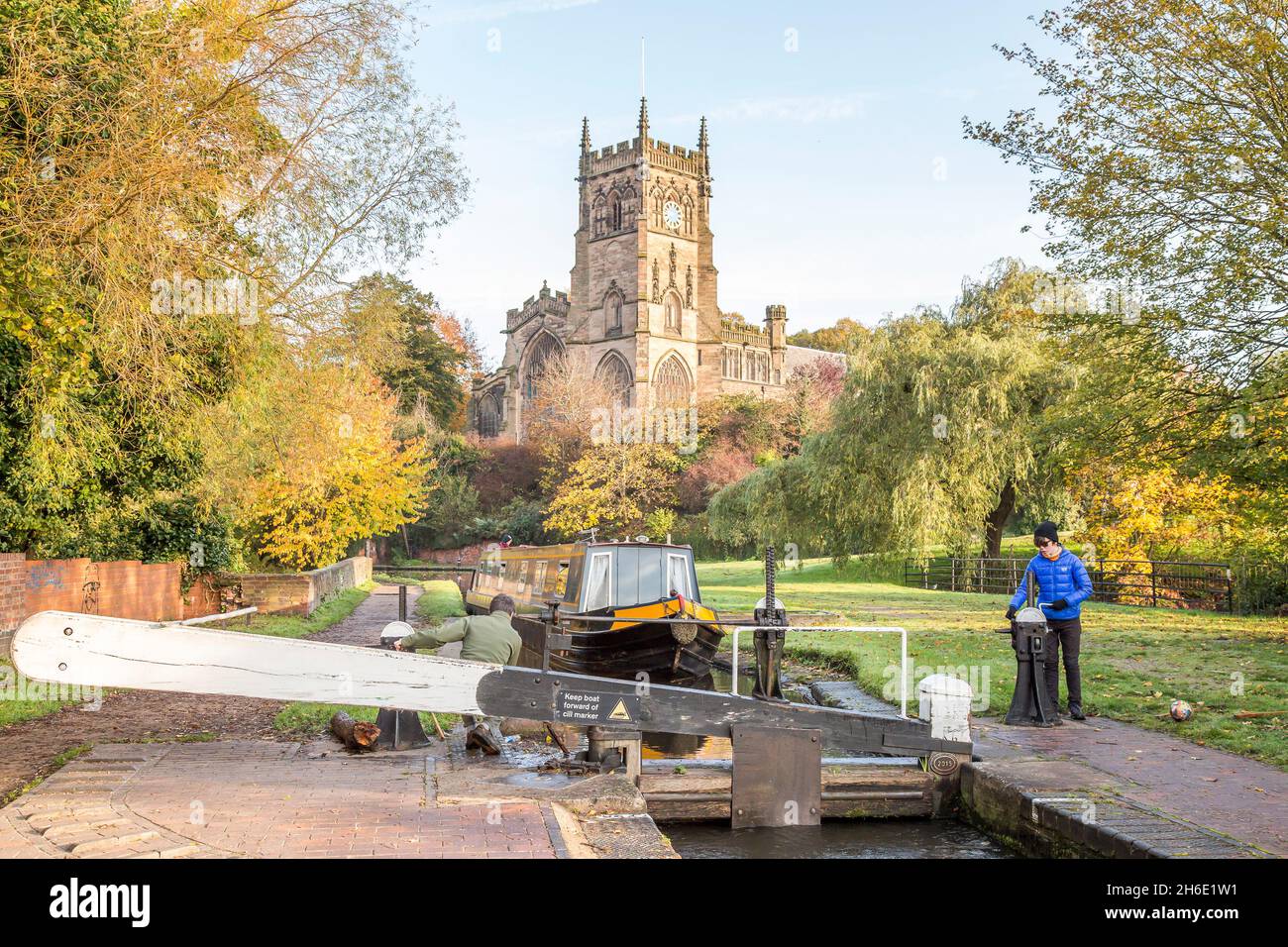 Narrowboat on the canal waterways approaching Kiddermister lock in summer with St Mary's church behind, Worcestershire, UK. Stock Photo