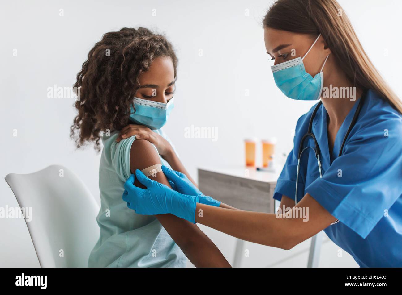 Medical Worker Vaccinating Black Pre-Adolescent Girl Making Vaccination In Clinic Stock Photo
