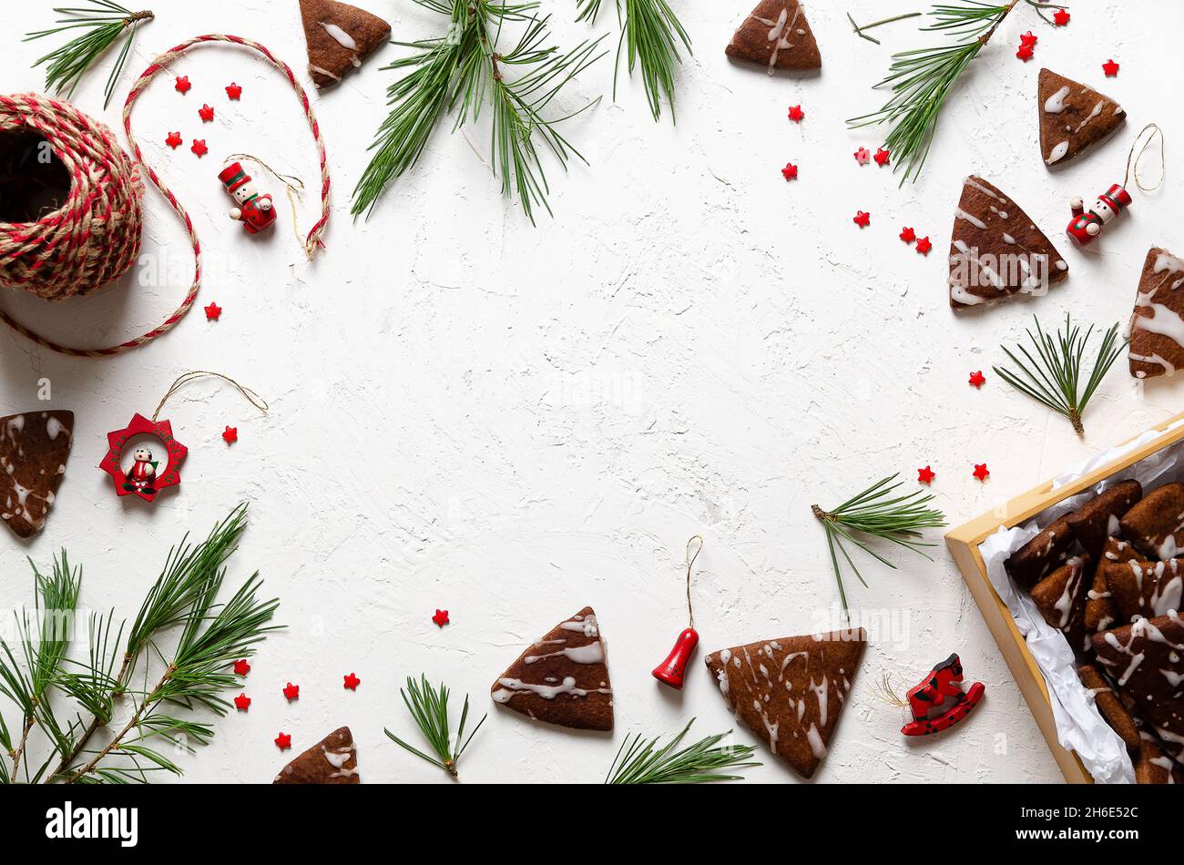 Pine branches, Christmas toys, little red stars, and chocolate cookies in a box and spread on a white background. Stock Photo