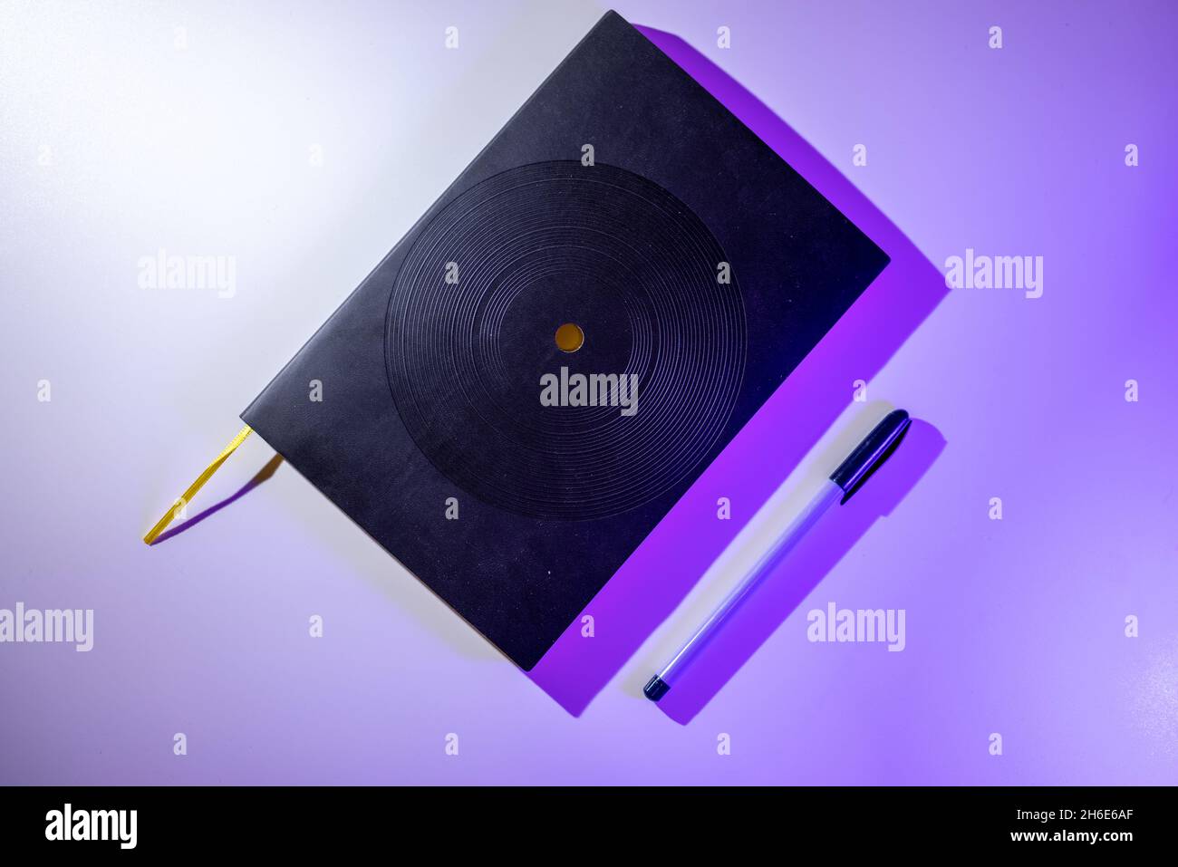 Black notebook with purple pen on purple background Stock Photo