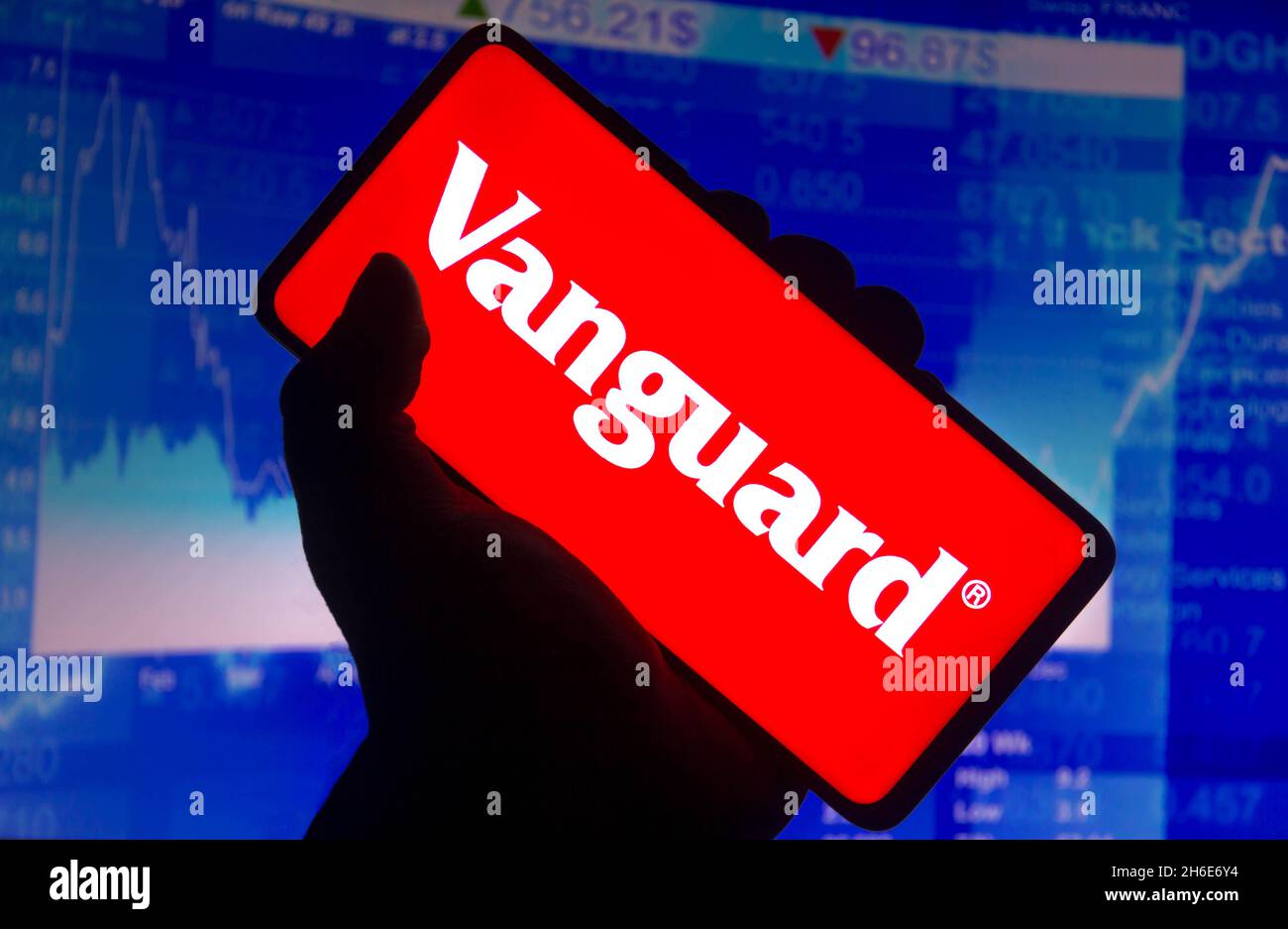 In this photo illustration the Vanguard Group logo displayed on a smartphone screen and a stock market graph in the background Stock Photo
