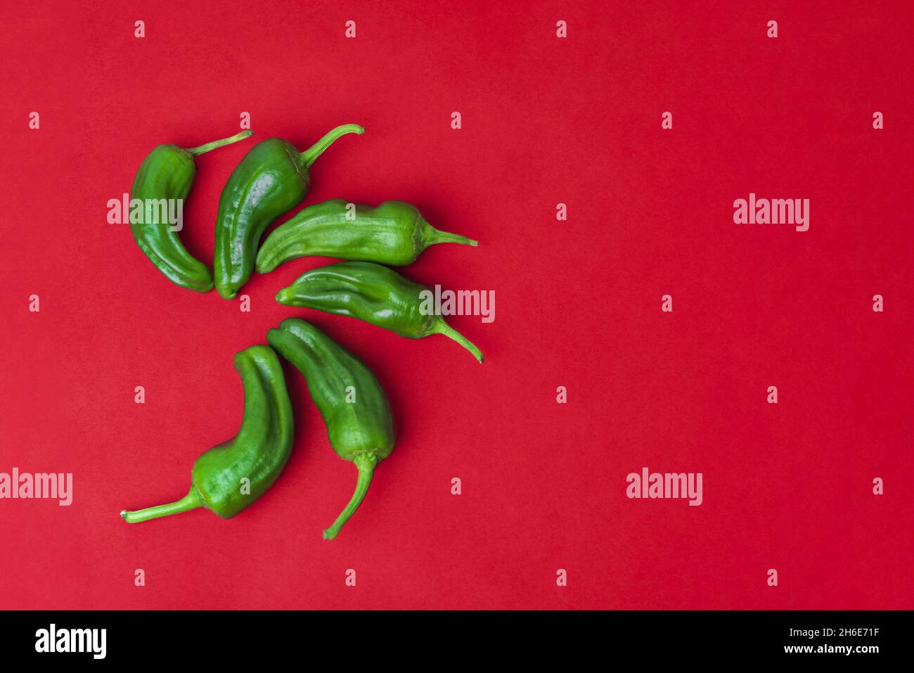 Top view of green chili peppers on a red background Stock Photo - Alamy