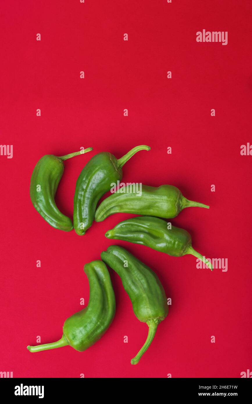 Top view of green chili peppers on a red background Stock Photo - Alamy