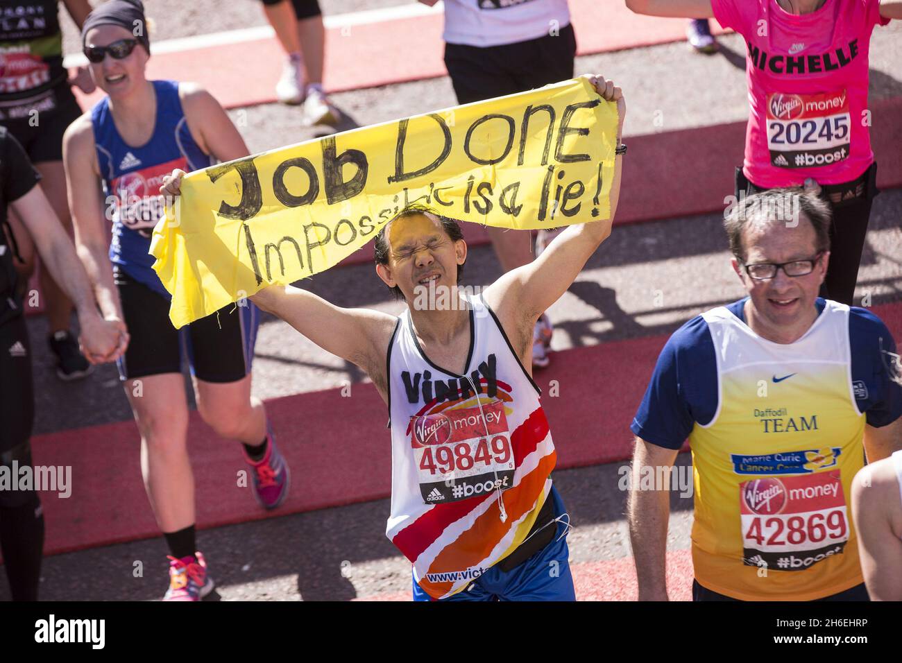 Runners at the finish line at the London Marathon, one holding a banner reading 'Job Done
