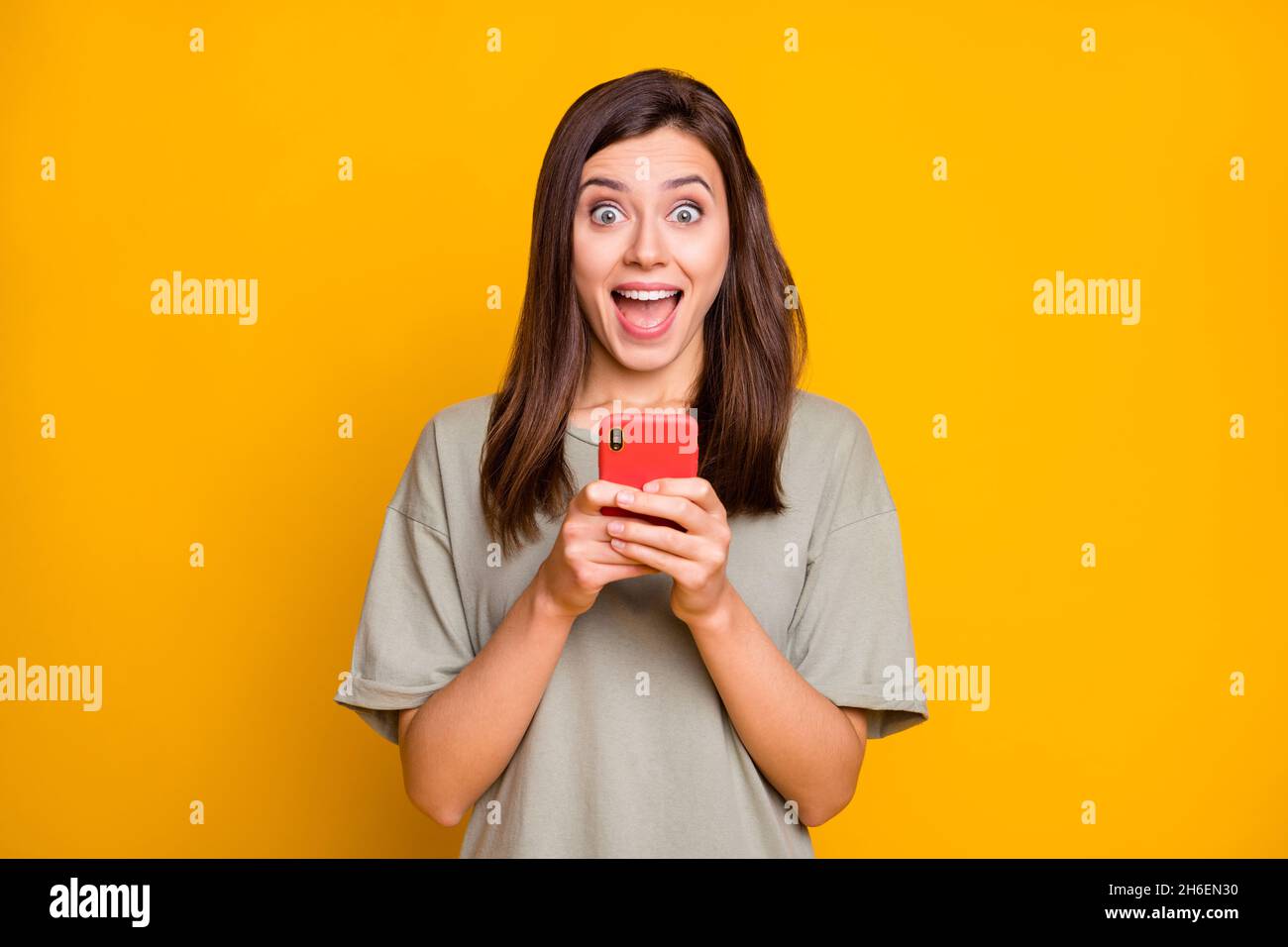 Portrait of pretty amazed cheerful brown-haired girl using device ...