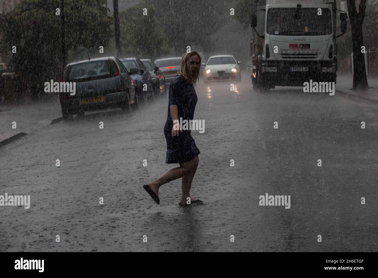 A woman gets caught in heavy rain in East London this afternoon Stock Photo