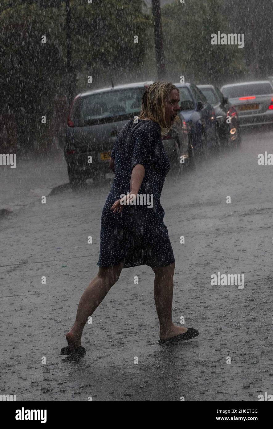 A woman gets caught in heavy rain in East London this afternoon Stock Photo