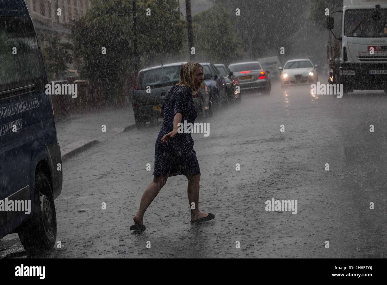 A woman gets caught in heavy rain in East London this afternoon Stock Photo