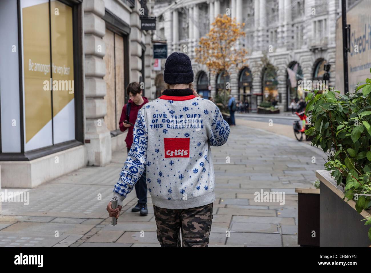 Homeless man wearing his 'Crisis' wooly jumper advertising the UK national charity for people experiencing homelessness, London, UK Stock Photo
