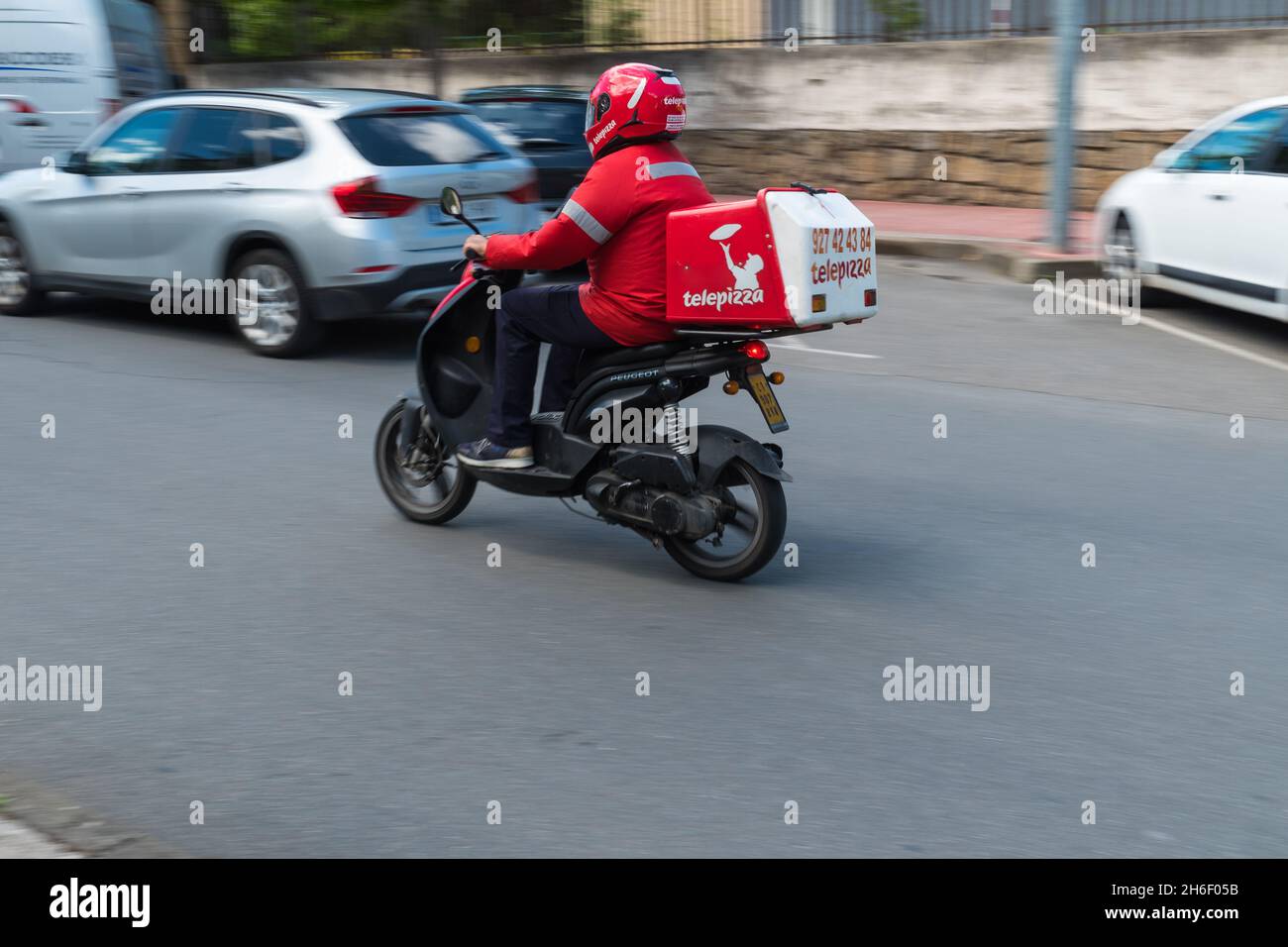 PLASENCIA, SPAIN - May 11, 2021: A pizza delivery man driving a Scooter-type motorcycle from the Telepizza chain delivers pizzas at home Stock Photo