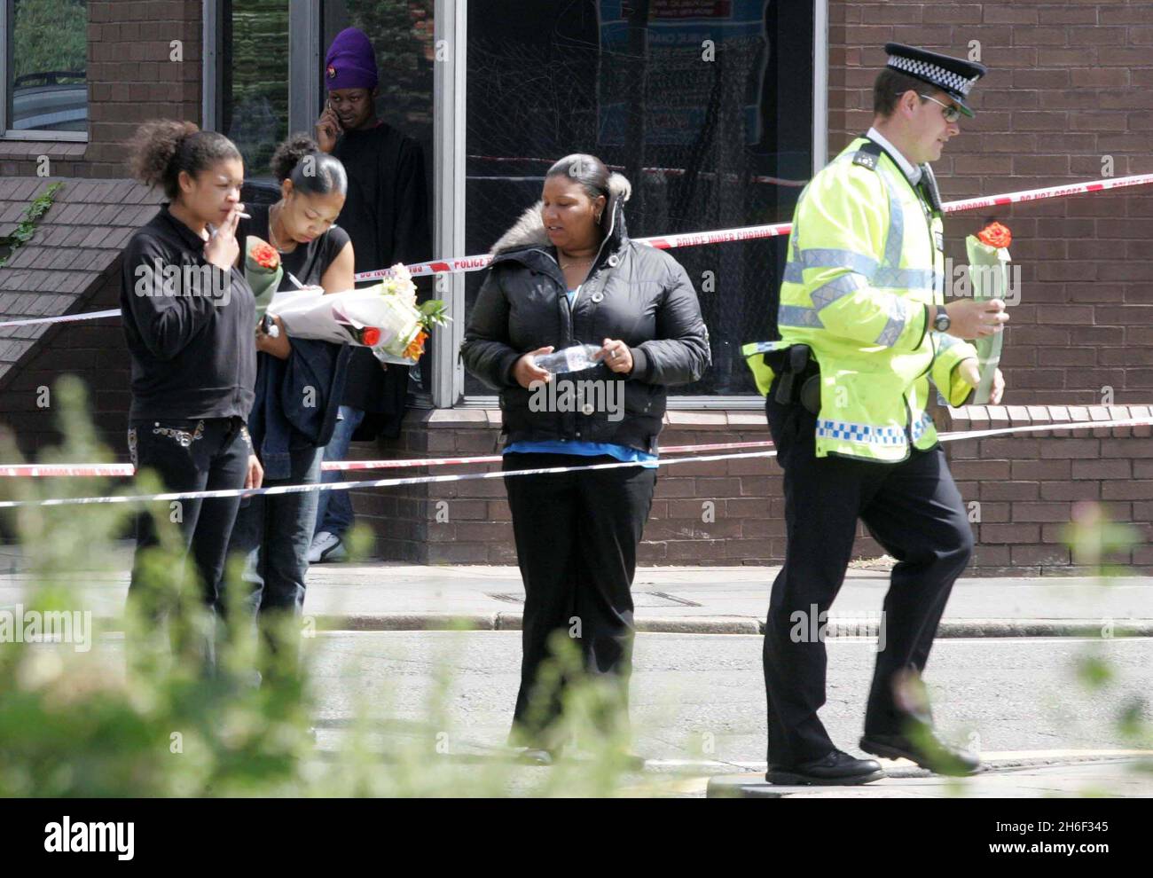 A police officer and friends of the victim laying flowers at the murder ...