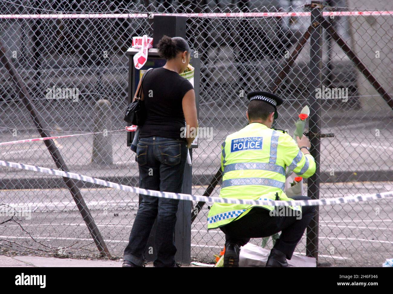 A police officer and friends of the victim laying flowers at the murder ...