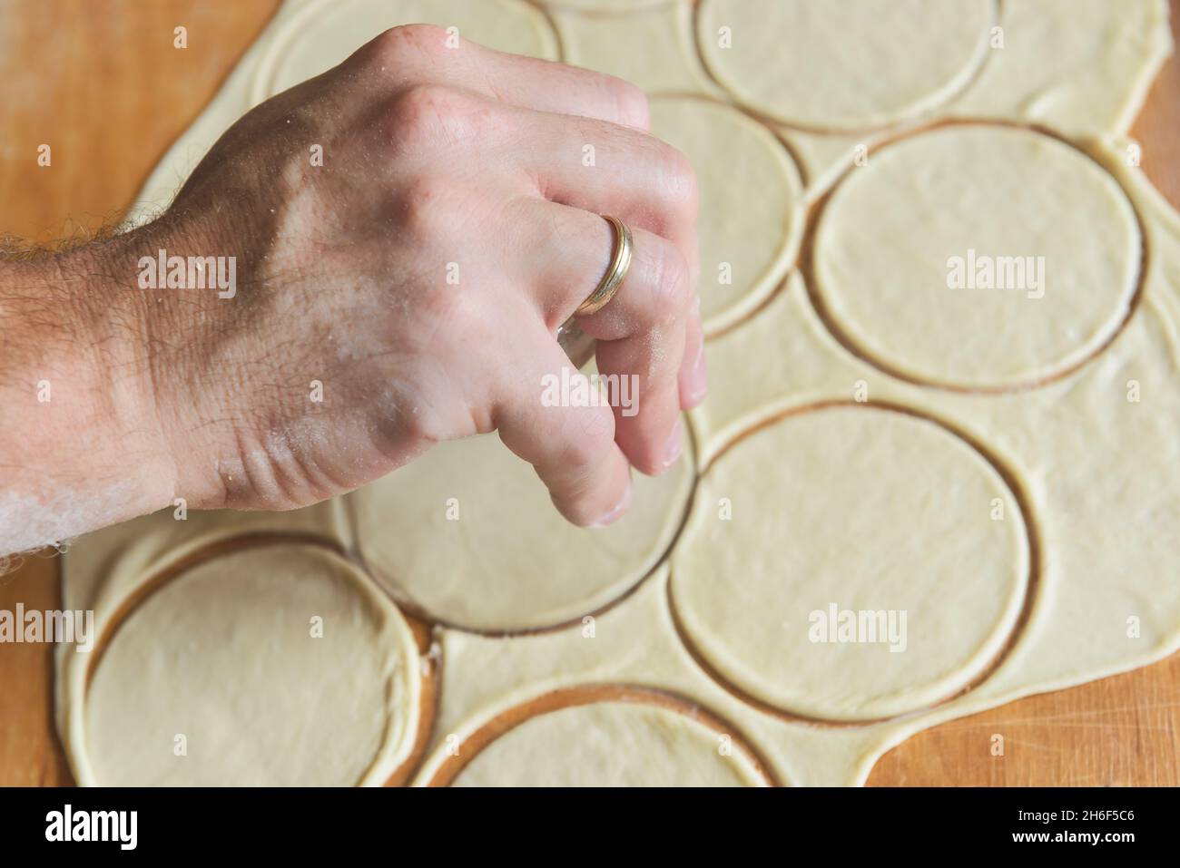 Making dumplings or pierogi, preparing rounded pieces of dough with glass Stock Photo