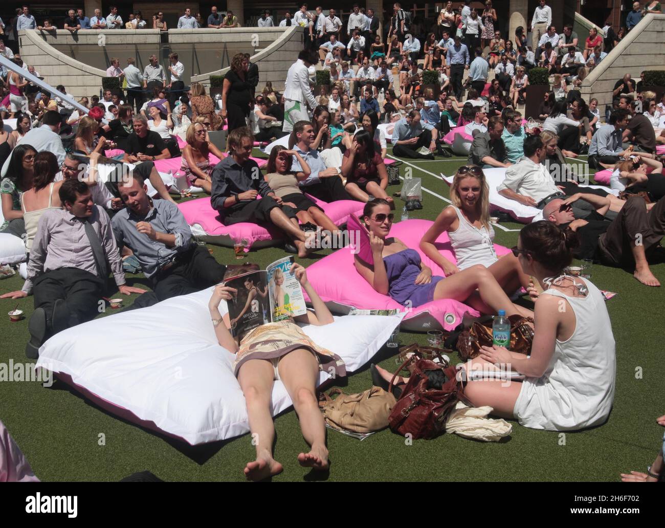 Office workers watch Wimbledon live as they sunbathe at Broadgate Circle, London Stock Photo