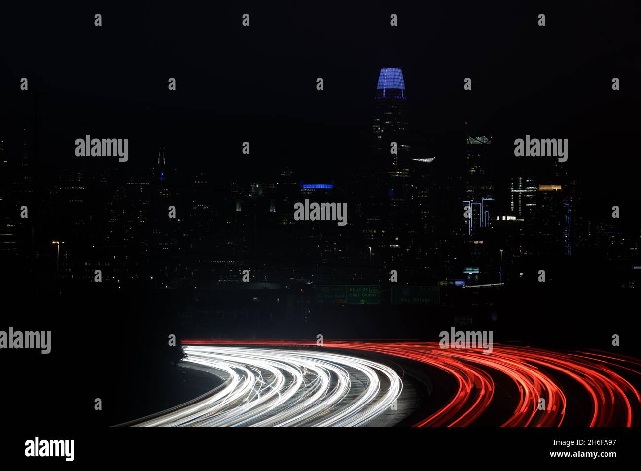 San Francisco Downtown and Car Light Trails on Highway Glow in the Dark. Stock Photo