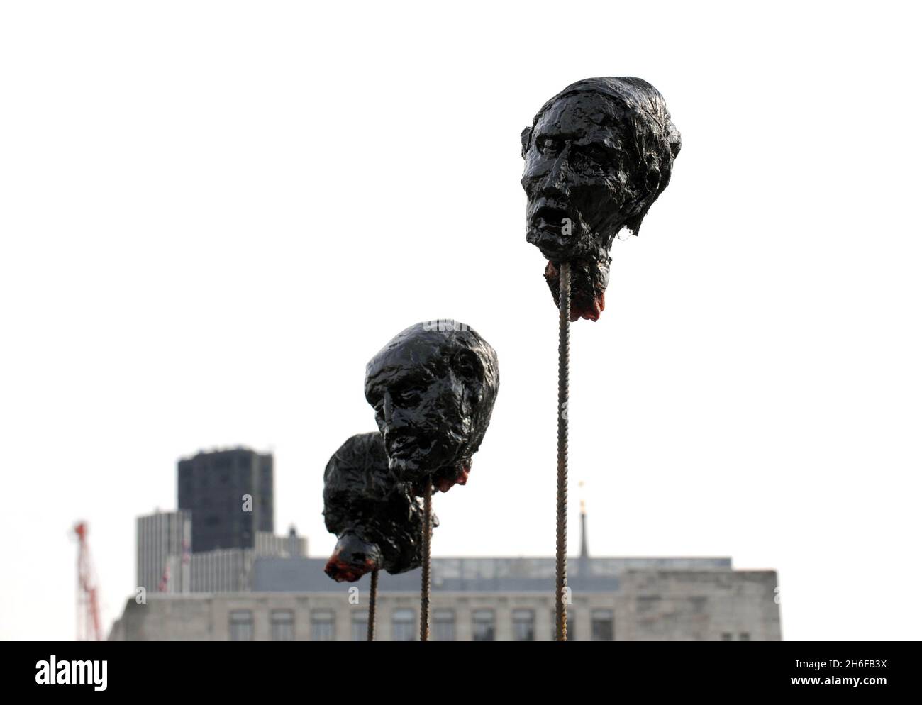 Commuters walk past artist David Fryer's 'Severed Heads' effigies of