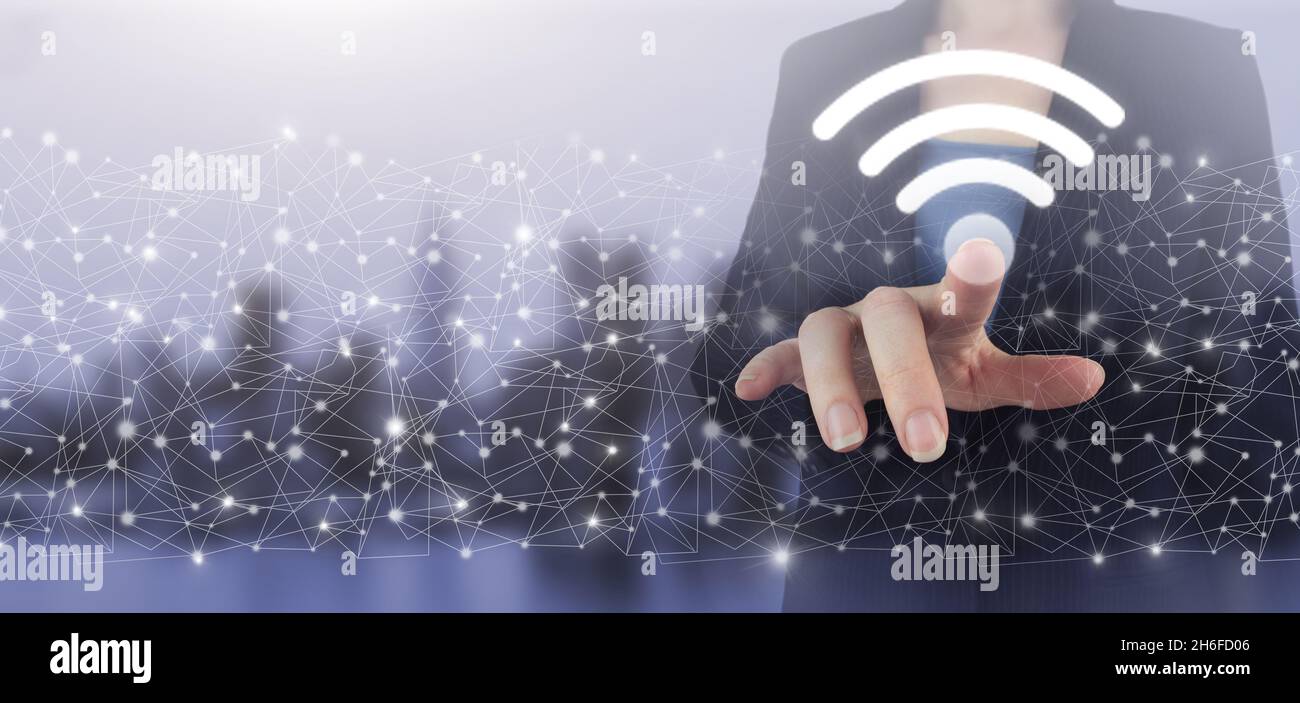 Business networking connection concept and Wi-Fi in city. Hand touch digital screen hologram Wi Fi sign on city light blurred background. Global world Stock Photo
