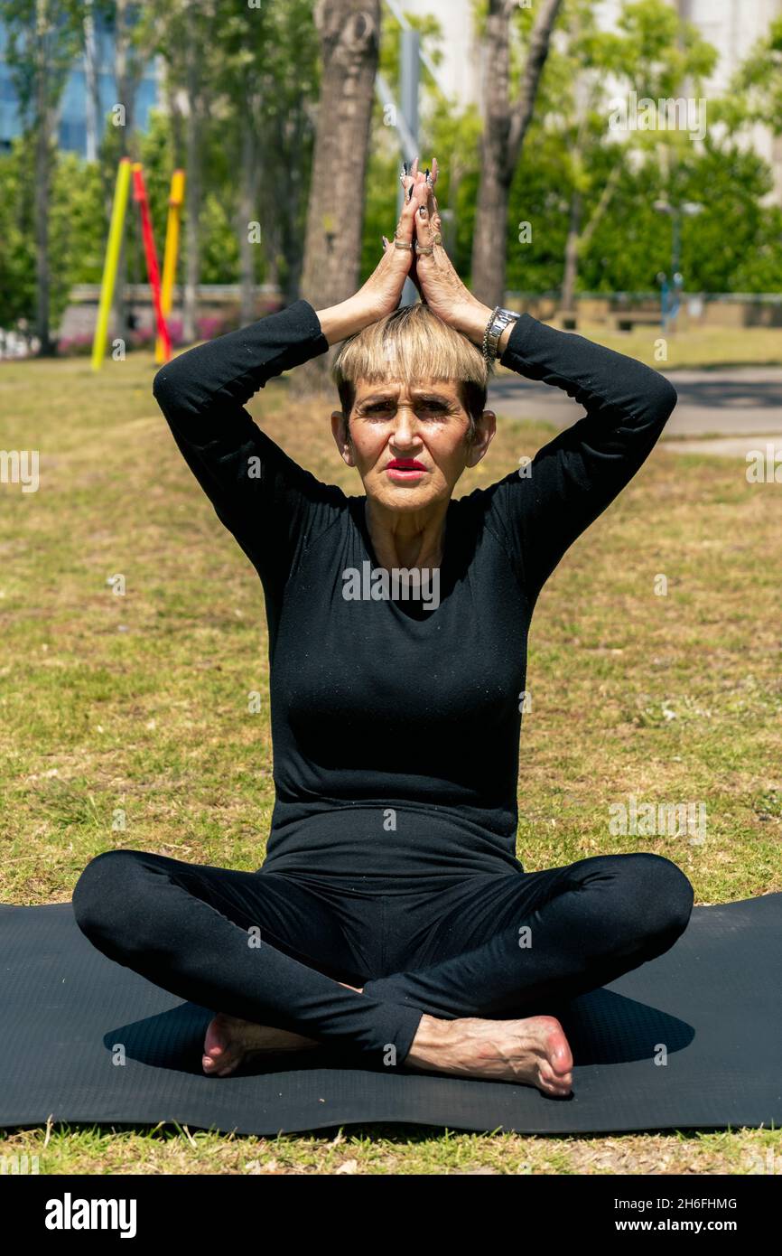 Mature adult woman sitting practicing yoga seeking greater concentration and directing her energy. Concept concentration, healthy life. Stock Photo
