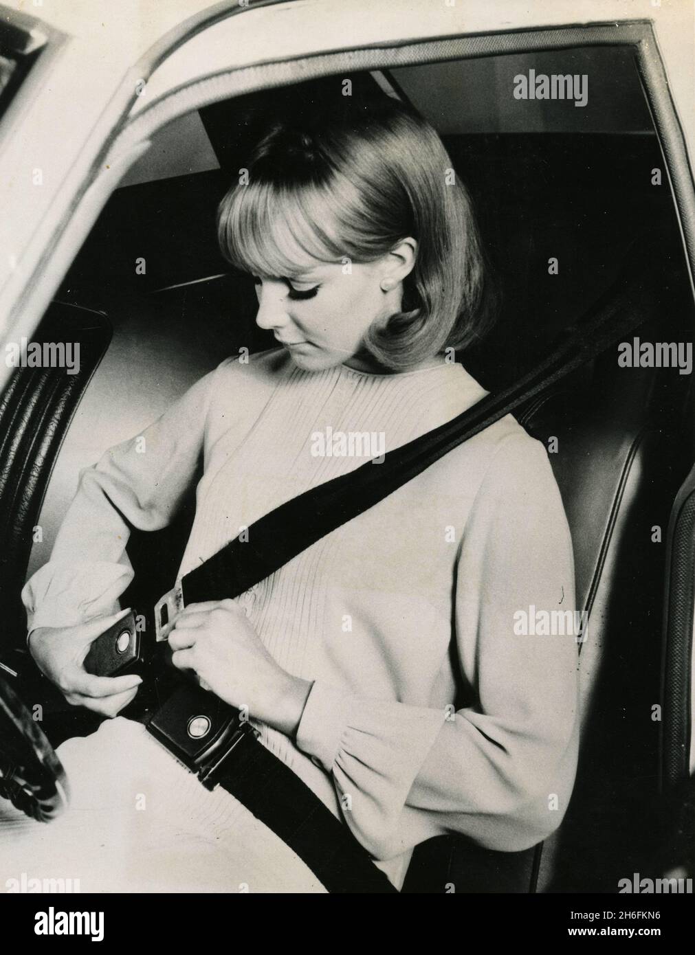 Model fastening the car seat belt advertising the obligation of safety belt for new cars, USA 1968 Stock Photo