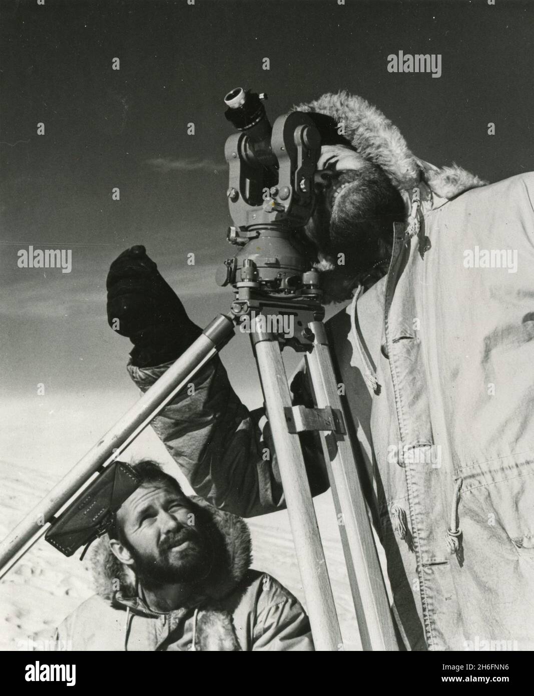 Topographic engineers of the US Geological Survey George Staeffler and Leslie Robinson using a theodolite to map Antarctica, Ross Sea 1962 Stock Photo