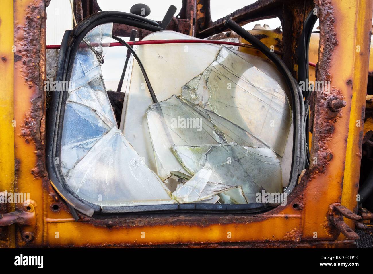 Close-up of a yellow rusty old disheveled tractor door with a shattered broken window pane, taken on Dungeness beach Kent UK, 14th of November 2021 Stock Photo