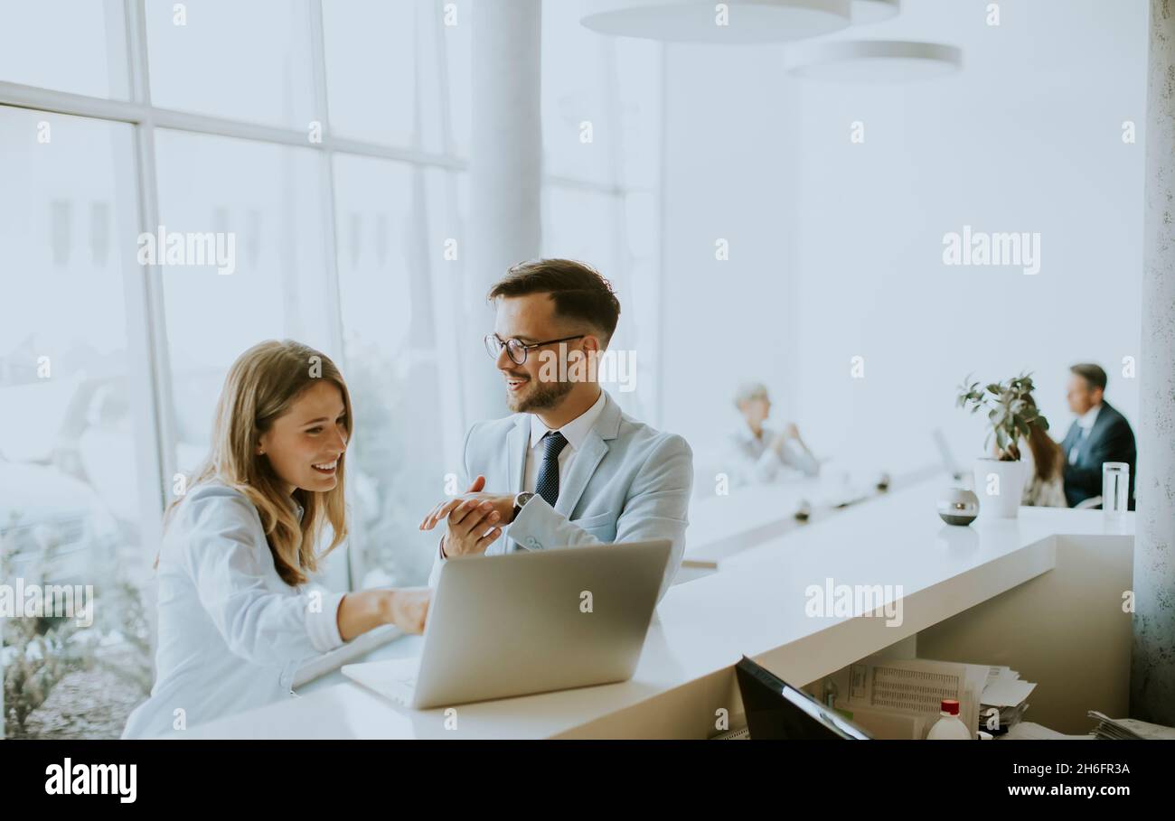 Young business couple working and discussing by laptop in the office in front of their team Stock Photo