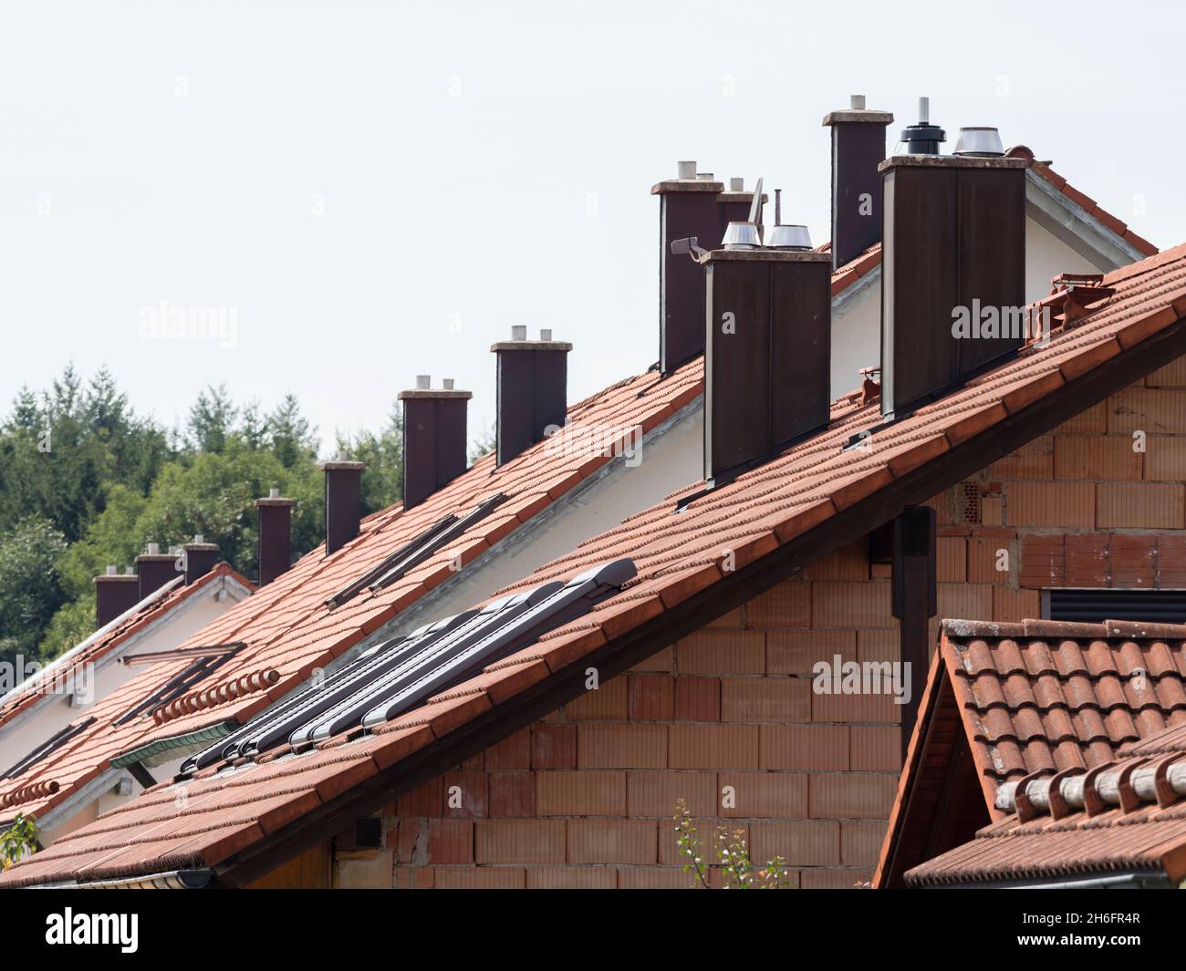 Roofs of many newly built residential houses in Germany with chimneys for oil- or gas-fired central heating. Stock Photo