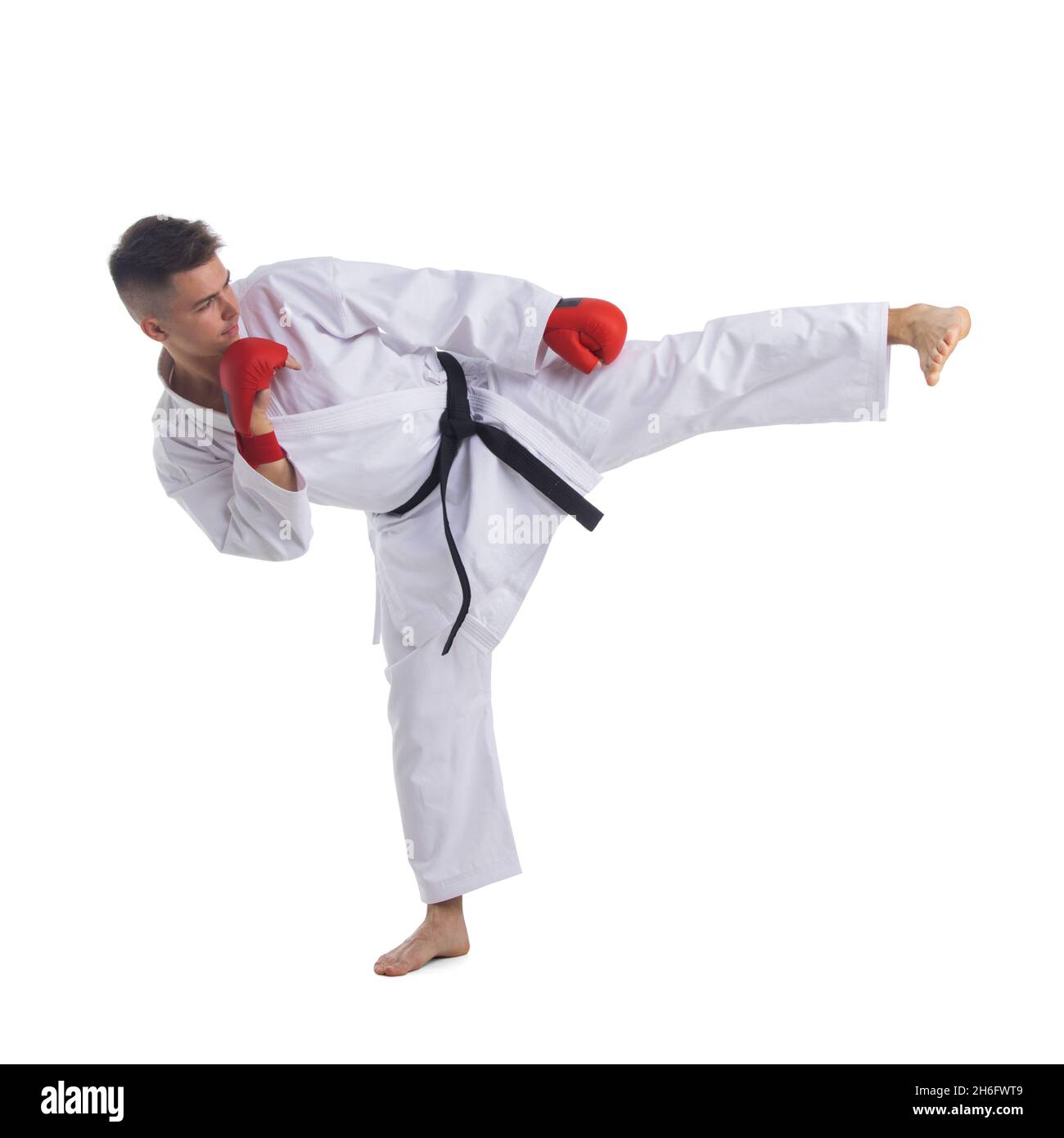 Black Belt TaeKwonDo Karate athlete man show traditional Fighting pose high leg kick in sport uniform white background isolated full length profile Stock Photo