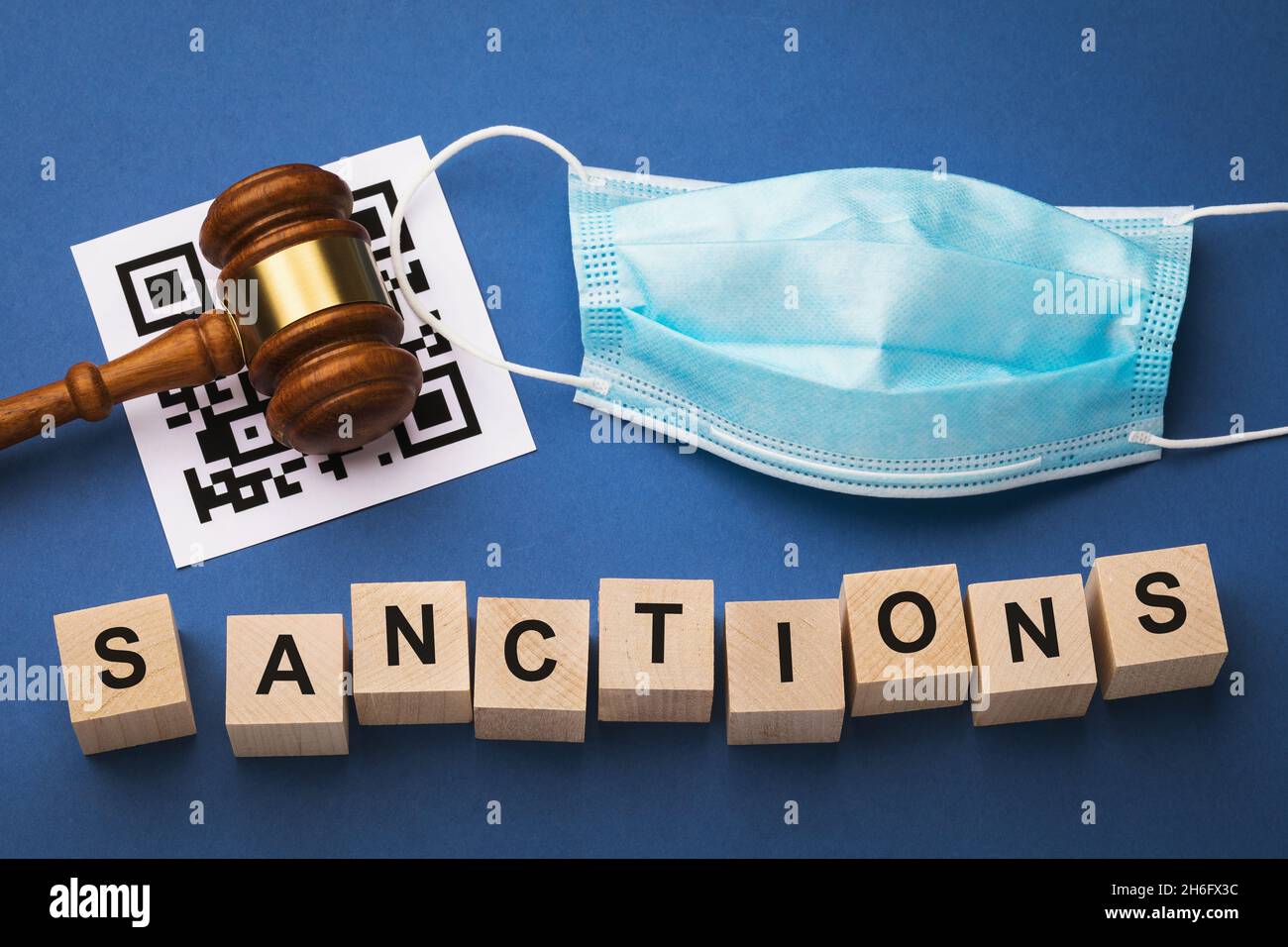 Judge gavel, barcode sheet, medical mask and wooden cubes with text on a blue background, the concept of sanctions for violation of the QR codes regim Stock Photo