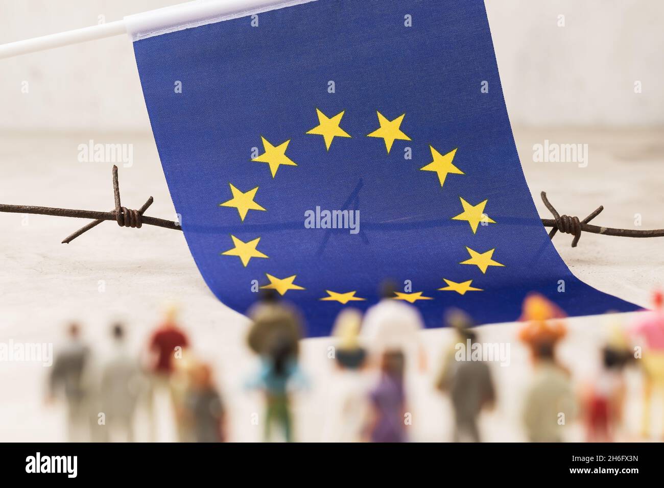 EU flag, barbed wire and plastic toy men out of focus, concept of illegal migration to the European Union Stock Photo