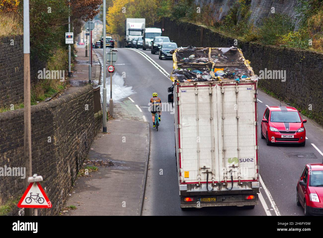 A cyclist passed closely by a waste recycling truck near Halifax, Calderdale, West Yorkshire .Close passes are not only really intimidating, but also dangerous: police attribute 'passing too close to the cyclist' as a contributory factor in a staggering 25% of serious collisions between cyclists and large vehicles. At the same time, we know that 62% of people in the UK consider cycling on the roads ‘too dangerous’. If we want safer roads for cyclists as well as more people cycling, putting an end to close passing is absolutely key, Stock Photo