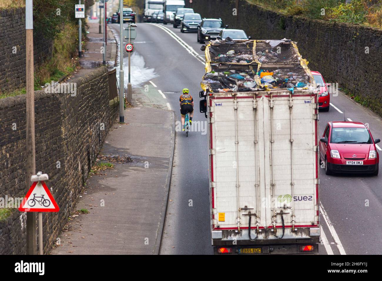 A cyclist passed closely by a waste recycling truck near Halifax, Calderdale, West Yorkshire .Close passes are not only really intimidating, but also dangerous: police attribute 'passing too close to the cyclist' as a contributory factor in a staggering 25% of serious collisions between cyclists and large vehicles. At the same time, we know that 62% of people in the UK consider cycling on the roads ‘too dangerous’. If we want safer roads for cyclists as well as more people cycling, putting an end to close passing is absolutely key, Stock Photo