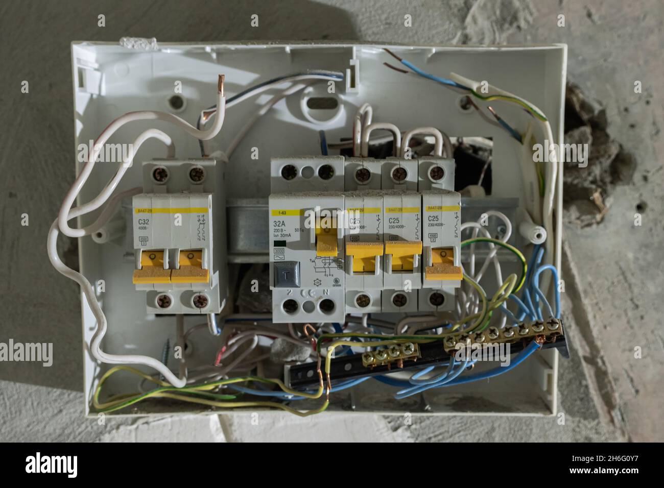 Open electrical panel with circuit breakers and carelessly laid wires