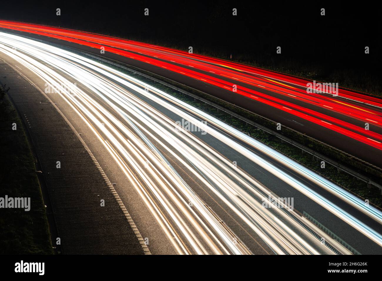 Light trails from a busy motorway or highway at night showing motion of traffic at rush hour. Traffic appears to drive on the right Stock Photo