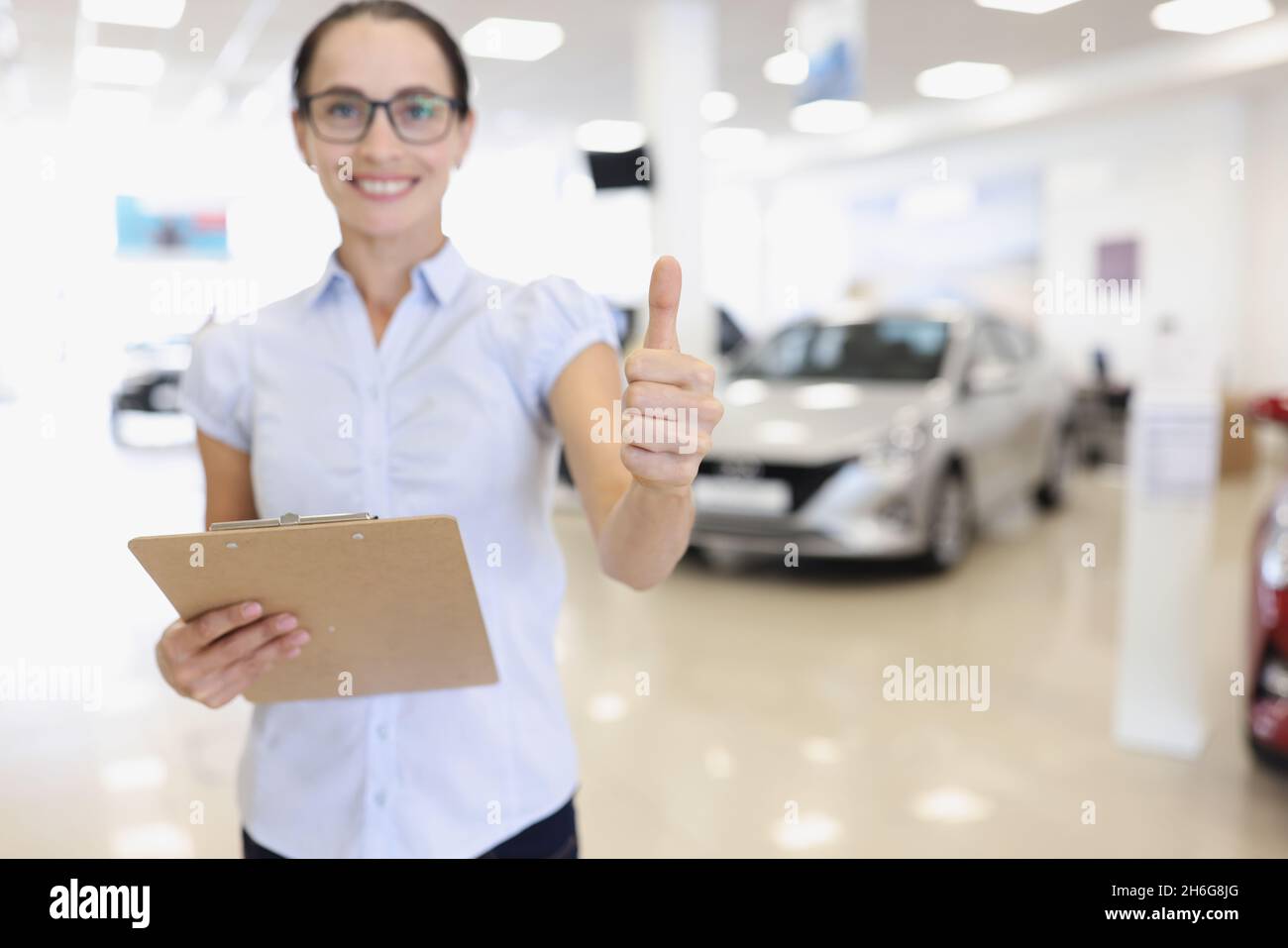 Car sales manager holds thumbs up in car dealership Stock Photo Alamy