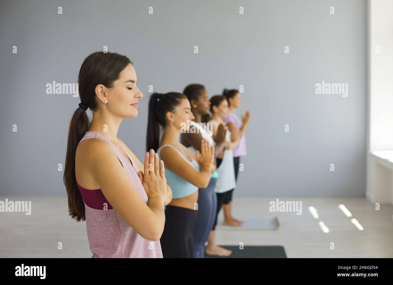 Calm happy woman meditating with their eyes closed together with other