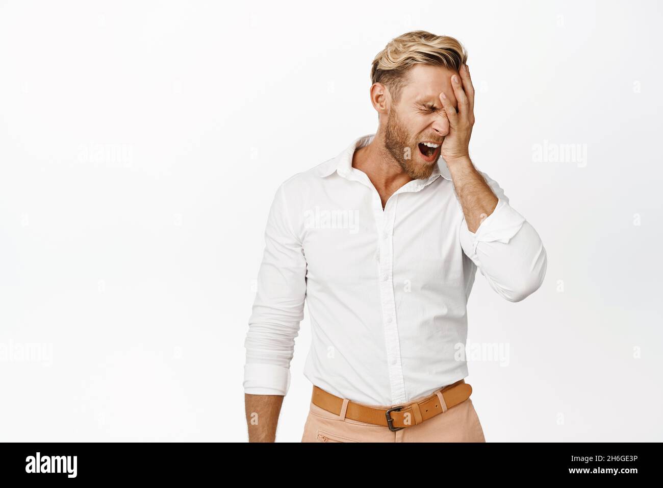 Failure. Frustrated blond man feeling disappointment, facepalm and screaming in despair, standing over white background Stock Photo