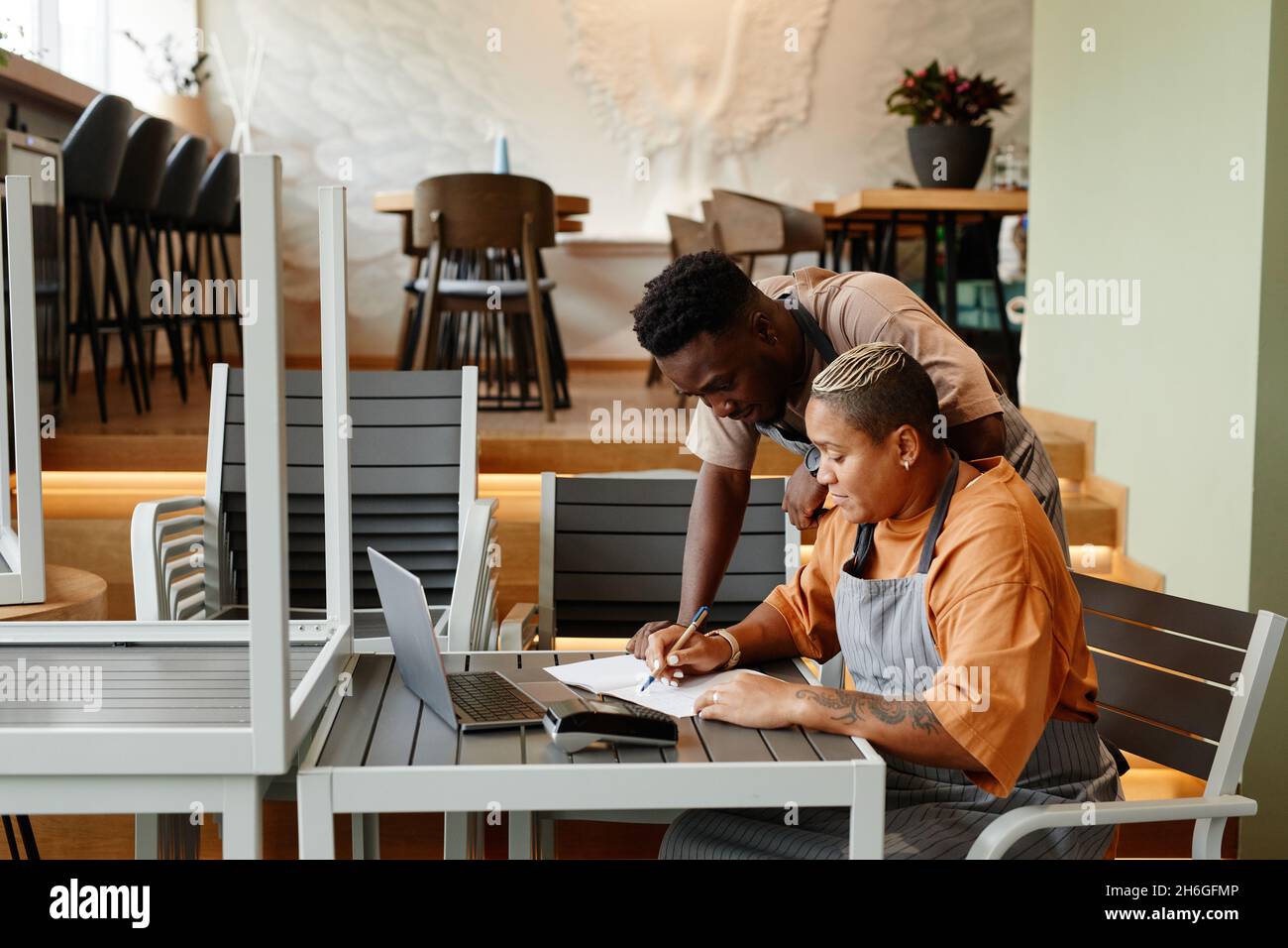 Young man and woman working together in modern cafe starting workday checking list of products for dishes and deciding what to order Stock Photo