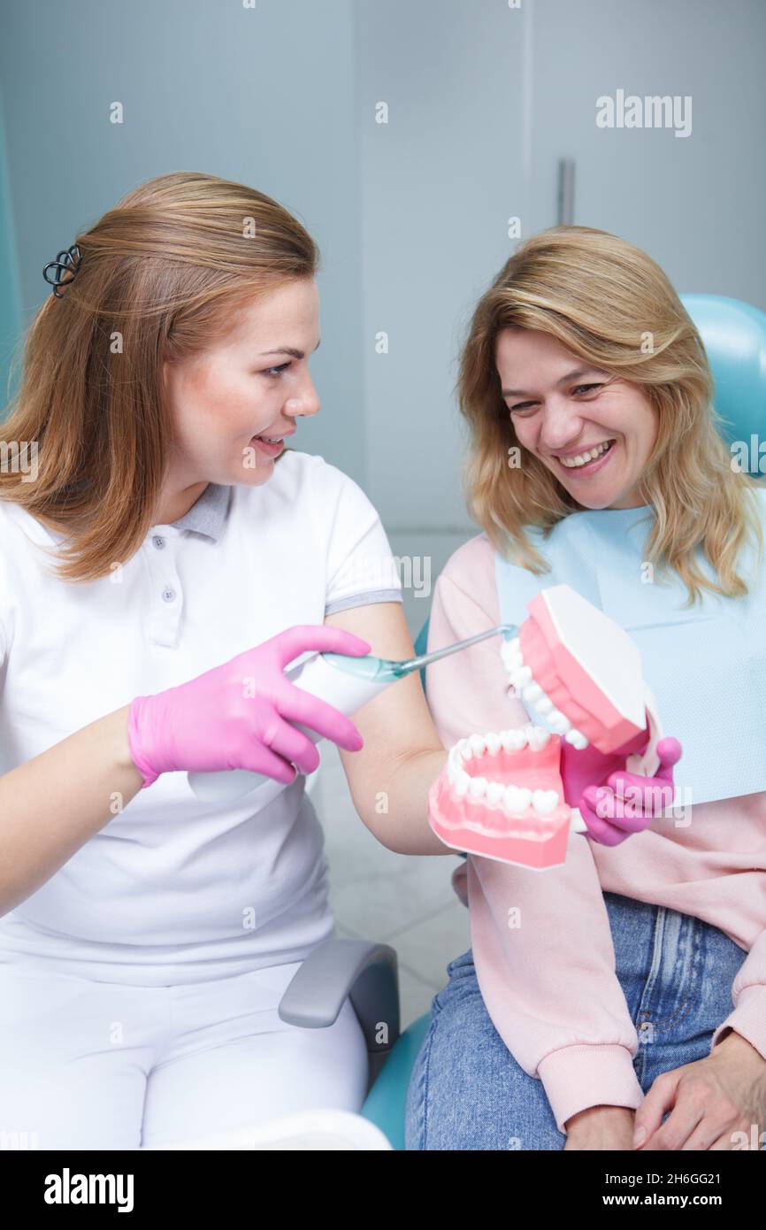 Vertical shot of a mature female patient learning how to use ultrasonic toothbrush from her dentist Stock Photo