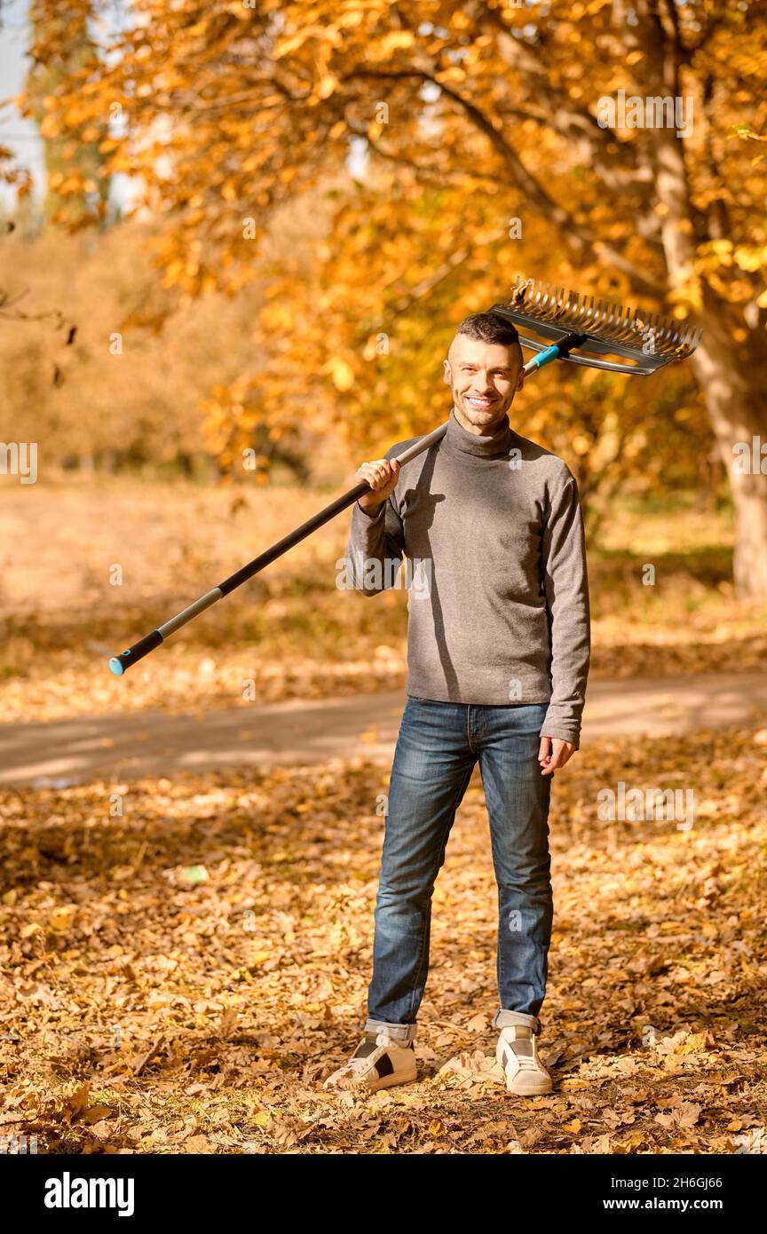 A man with a rake standing in the park Stock Photo Alamy